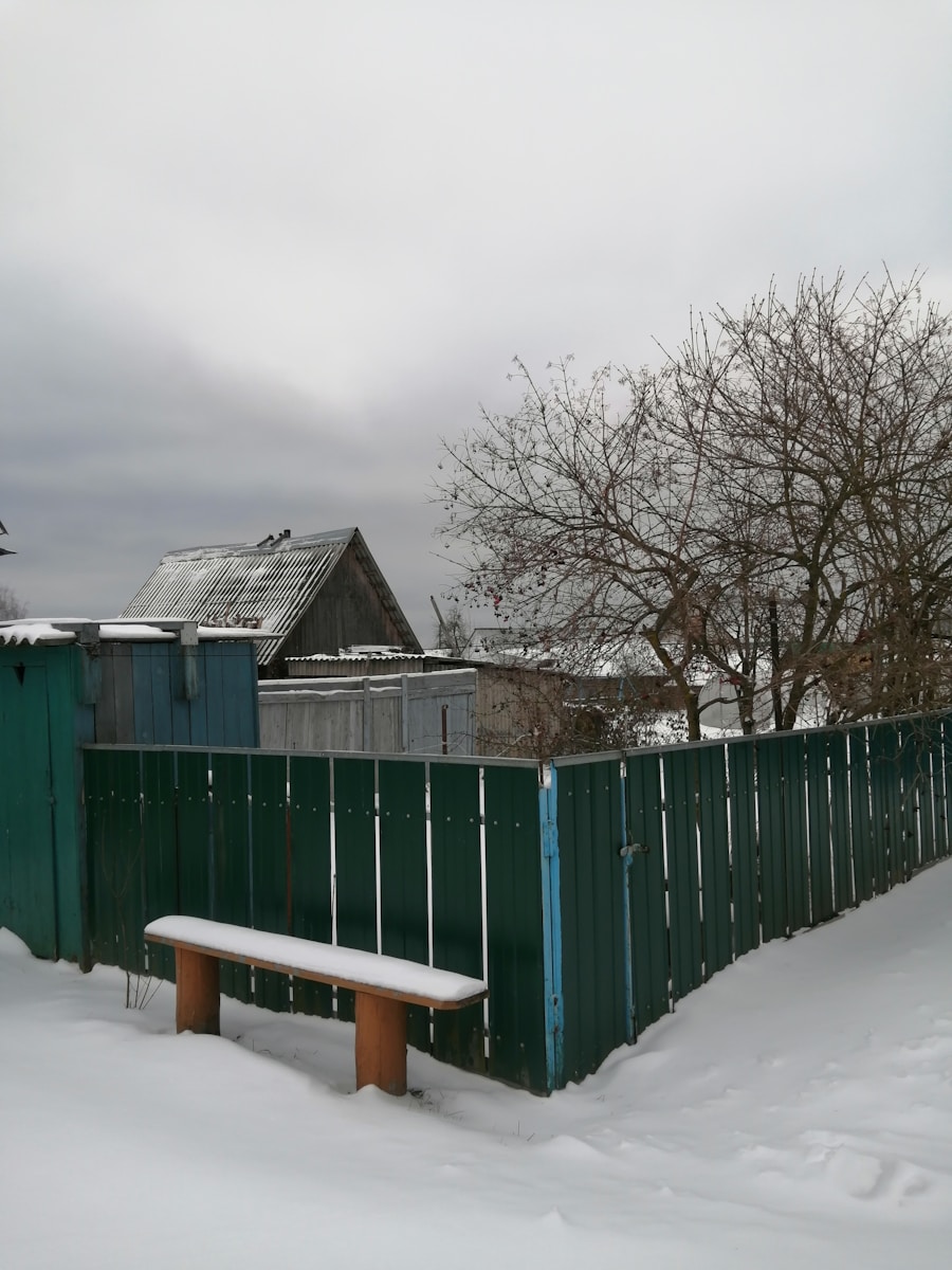 a snow covered park bench next to a fence