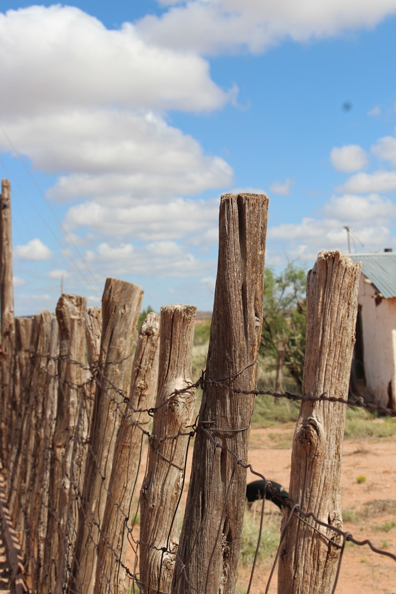 a fence with a wire fence and a building in the background