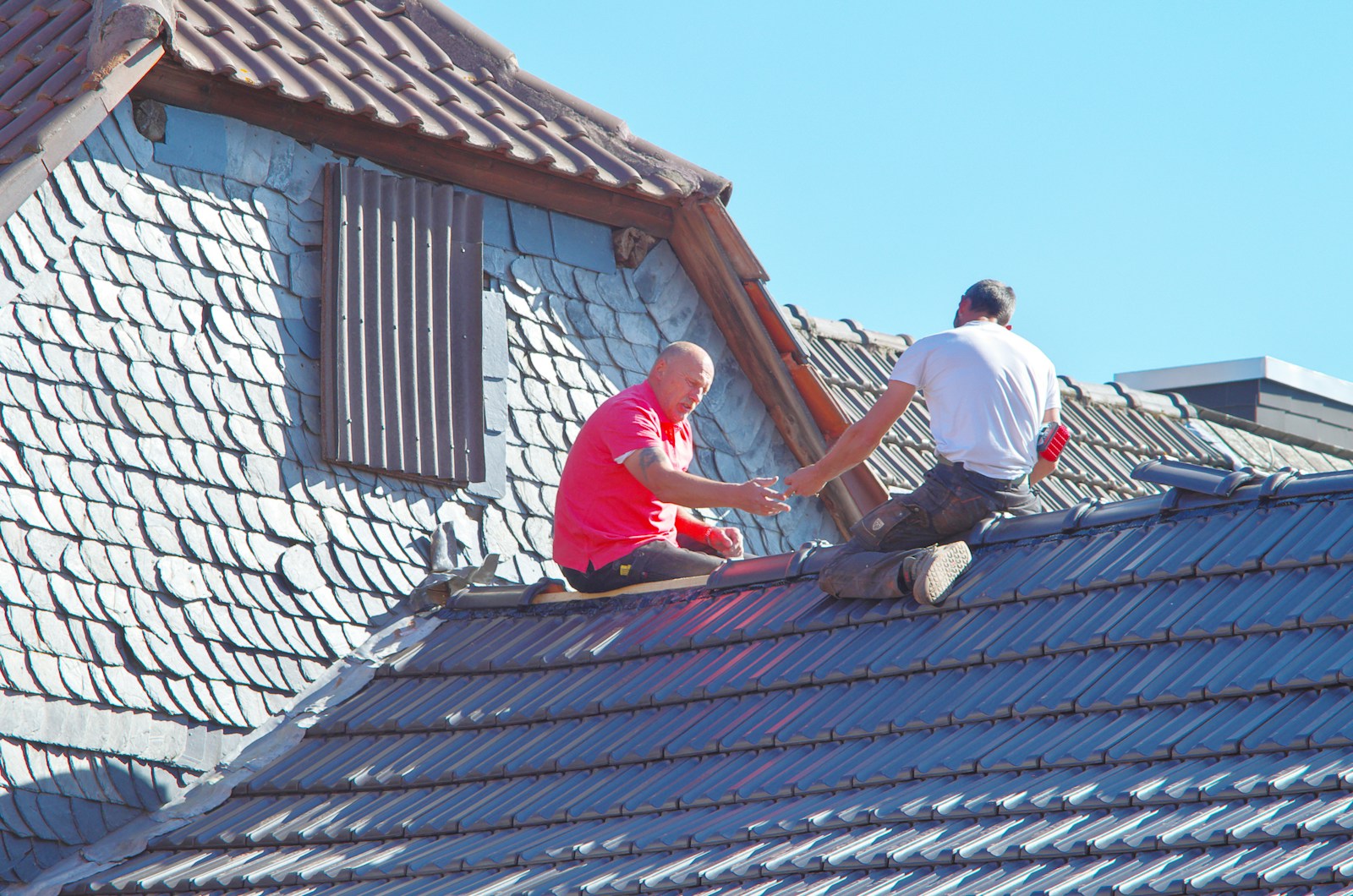 two men working on the roof of a house