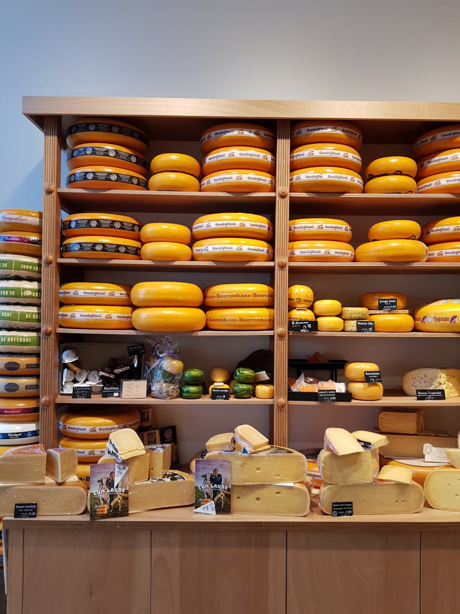 Showcase of a variety of cheeses on wooden shelves in a Dutch shop.